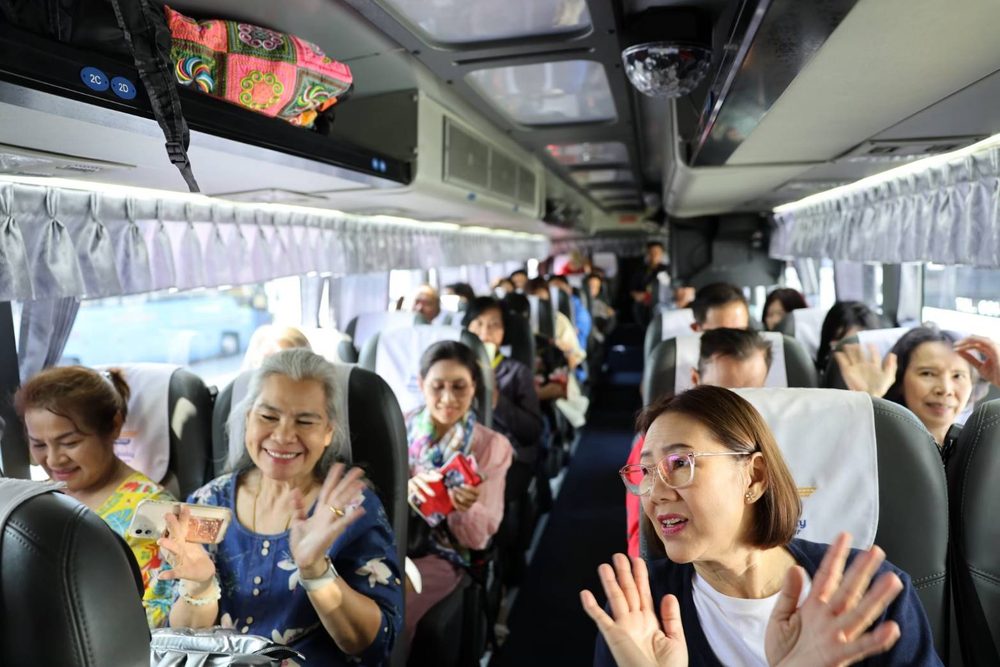 ผู้โดยสารยิ้มและโบกมือบนรถบัสรับส่งไปท่าเรือแหลมฉบัง